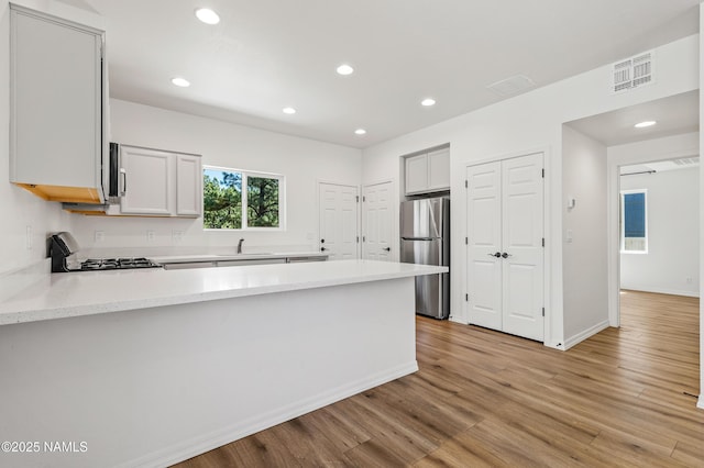 5026 E Retreat Cir, Flagstaff, AZ 86004 - kitchen with freestanding refrigerator, white range with gas stovetop, a peninsula, recessed lighting, and light wood-style floors