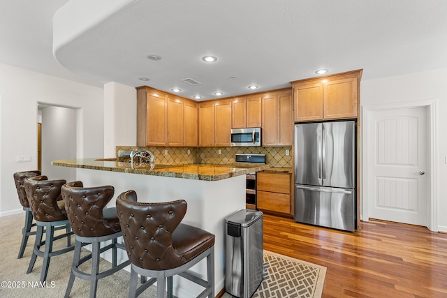 4759 W Quick Draw, Flagstaff, AZ 86005 - kitchen featuring appliances with stainless steel finishes, dark stone counters, a breakfast bar, backsplash, and a peninsula