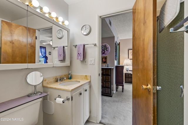 bathroom featuring a textured ceiling, toilet, and vanity