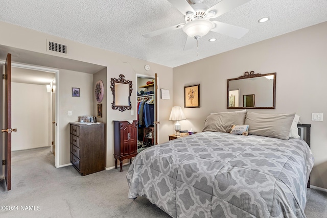 bedroom with a closet, ceiling fan, a walk in closet, and a textured ceiling