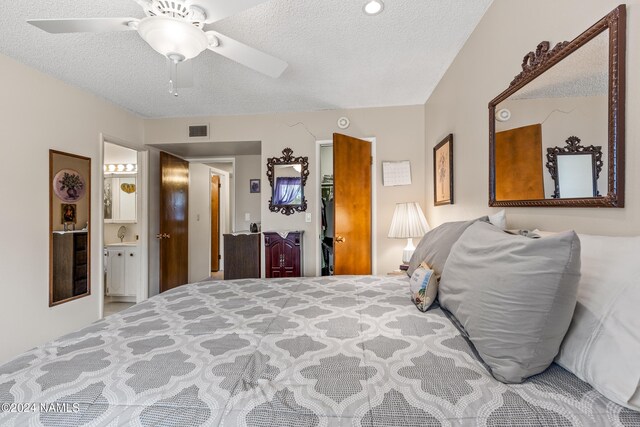 bedroom with ceiling fan, a textured ceiling, ensuite bathroom, and a closet