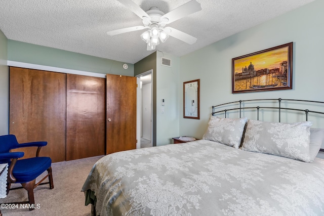 carpeted bedroom featuring a textured ceiling, a closet, and ceiling fan