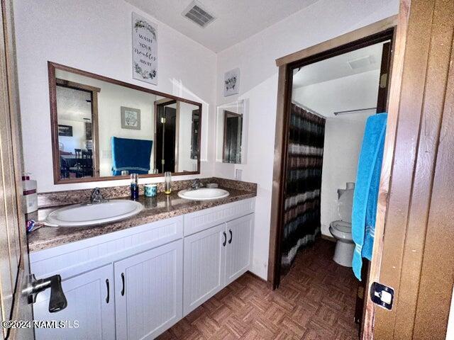 bathroom featuring vanity, toilet, and parquet flooring