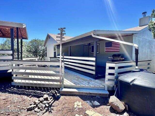 view of side of home featuring a wooden deck and a hot tub