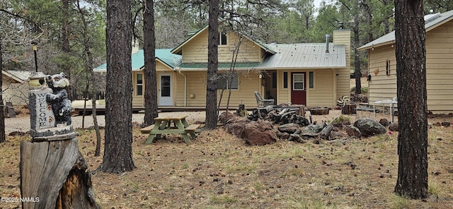view of front of property with a porch, a chimney, and metal roof