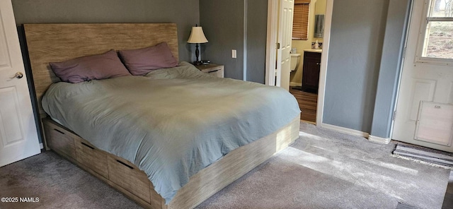 carpeted bedroom featuring baseboards and ensuite bathroom