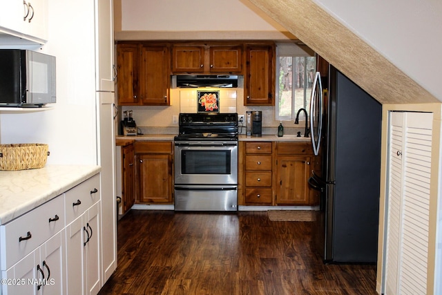 kitchen featuring brown cabinetry, freestanding refrigerator, dark wood-style flooring, range hood, and electric range