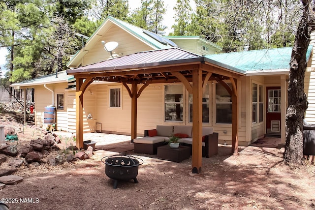 rear view of house with an outdoor living space with a fire pit, a patio, and metal roof