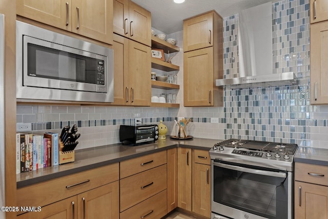 kitchen featuring appliances with stainless steel finishes, wall chimney range hood, open shelves, tasteful backsplash, and dark countertops