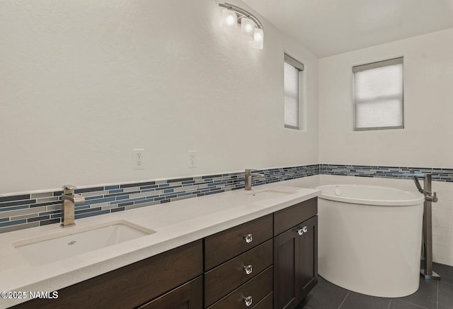 bathroom featuring a freestanding bath, tile walls, a sink, and wainscoting