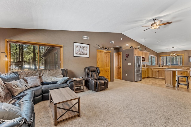 living area with lofted ceiling, light carpet, visible vents, and ceiling fan with notable chandelier