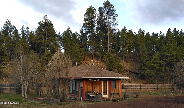 1600 S River Valley Rd, Flagstaff, AZ 86004 - rear view of house with roof with shingles, a forest view, fence, and an outdoor structure