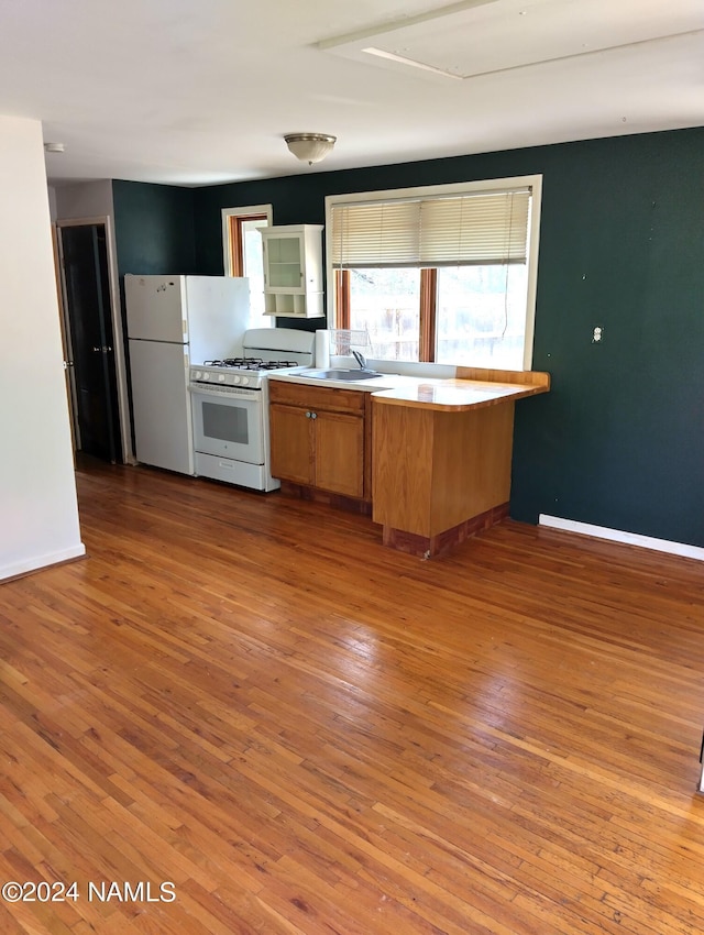 1600 S River Valley Rd, Flagstaff, AZ 86004 - kitchen with baseboards, white appliances, a peninsula, wood-type flooring, and a sink