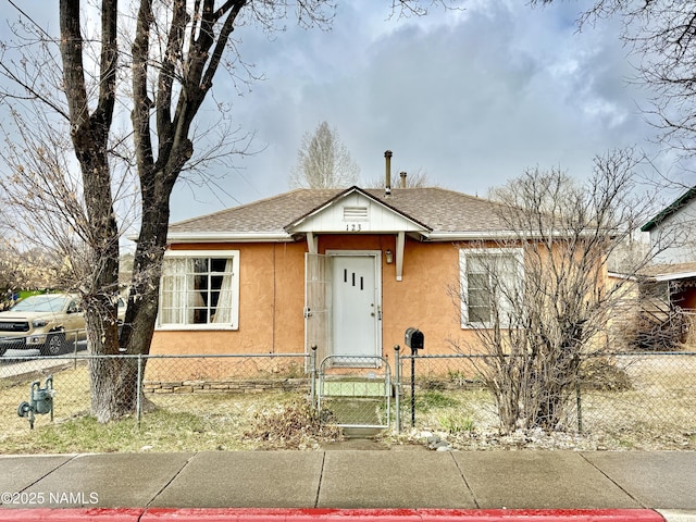 bungalow with a fenced front yard, a gate, roof with shingles, and stucco siding