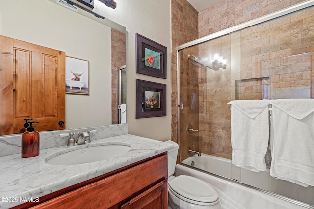 full bathroom with enclosed tub / shower combo, vanity, and toilet