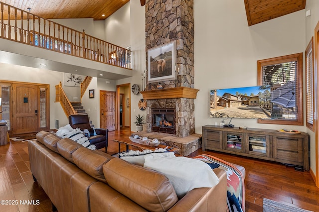 living room with wood ceiling, dark hardwood / wood-style floors, high vaulted ceiling, and a stone fireplace