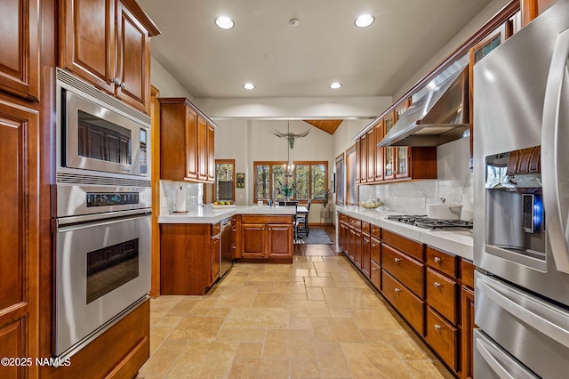 kitchen with tasteful backsplash, decorative light fixtures, ventilation hood, kitchen peninsula, and stainless steel appliances