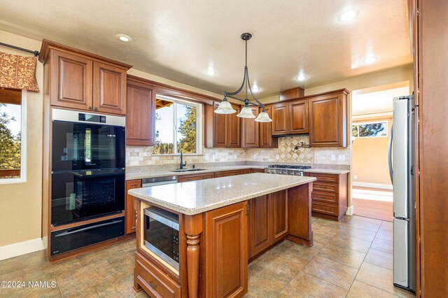 kitchen featuring a center island, sink, decorative light fixtures, stainless steel appliances, and light stone counters