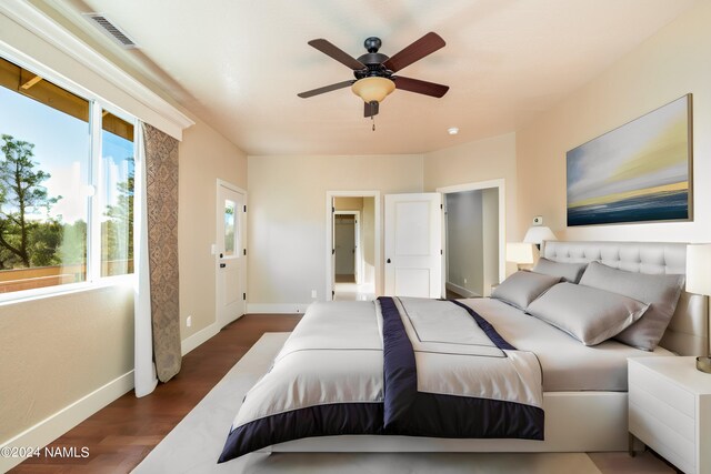 bedroom featuring ceiling fan, dark hardwood / wood-style floors, and multiple windows