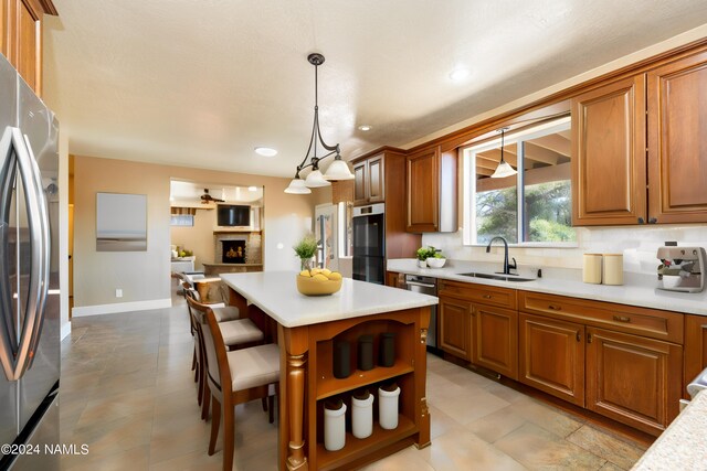 kitchen featuring pendant lighting, appliances with stainless steel finishes, sink, a center island, and a breakfast bar area