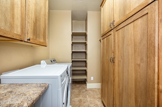 clothes washing area featuring washer and dryer and cabinets