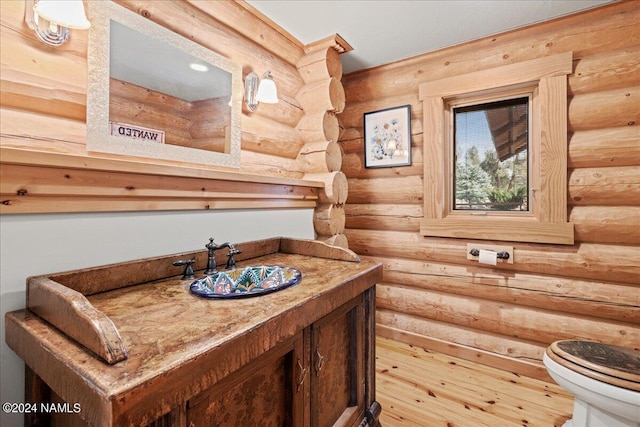 bathroom featuring toilet, vanity, and log walls