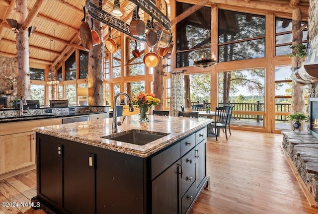 kitchen with sink, light wood-type flooring, wooden ceiling, high vaulted ceiling, and an island with sink