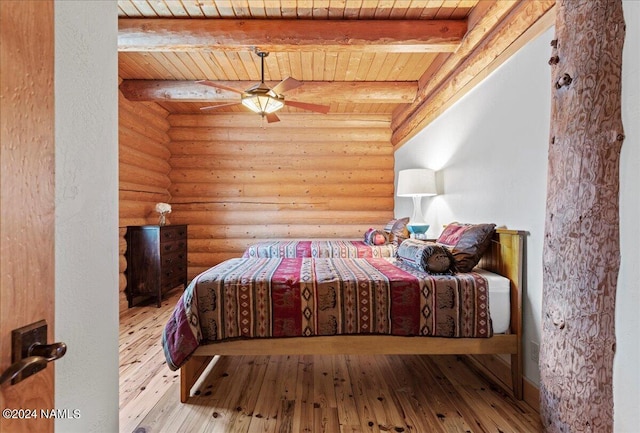 bedroom with wood ceiling, ceiling fan, rustic walls, and beamed ceiling