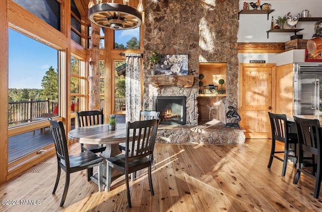 dining area featuring a high ceiling, light hardwood / wood-style flooring, and a fireplace