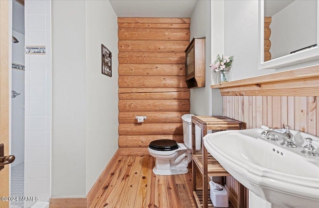 bathroom with sink, hardwood / wood-style flooring, rustic walls, and toilet