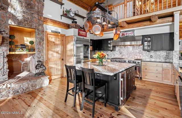 kitchen featuring wall chimney exhaust hood, backsplash, a high ceiling, a kitchen island, and high end appliances