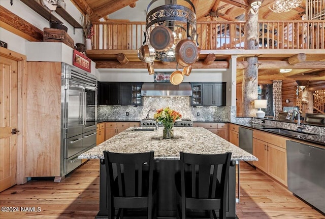 kitchen featuring beamed ceiling, appliances with stainless steel finishes, sink, light stone counters, and light brown cabinets