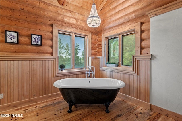 bathroom featuring a healthy amount of sunlight, rustic walls, and a bathtub