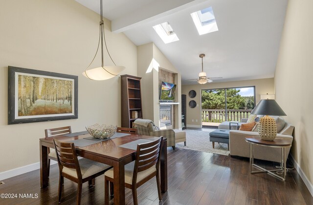 dining space with ceiling fan, lofted ceiling with skylight, and dark hardwood / wood-style flooring