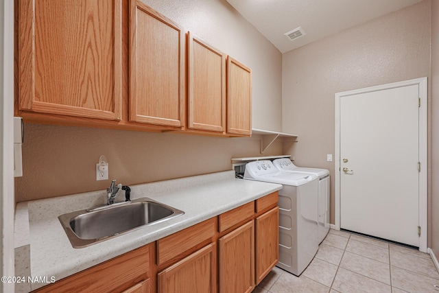 laundry area featuring cabinets, sink, light tile patterned floors, and washing machine and clothes dryer