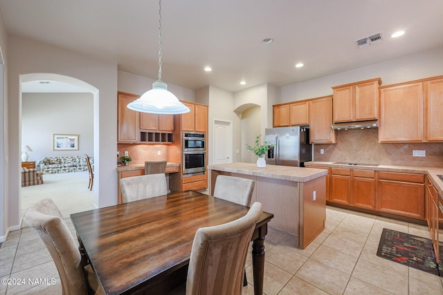 kitchen featuring a kitchen island, stainless steel appliances, backsplash, hanging light fixtures, and light tile patterned floors