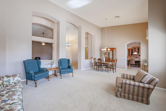 living area featuring a notable chandelier, a towering ceiling, and carpet floors