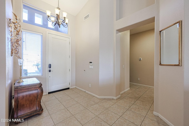 foyer entrance with a chandelier, light tile patterned floors, and lofted ceiling