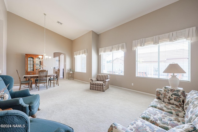 living room featuring carpet floors, high vaulted ceiling, and an inviting chandelier