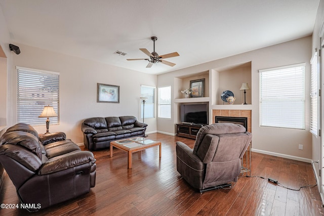 living room with a wealth of natural light, dark hardwood / wood-style floors, and a tiled fireplace