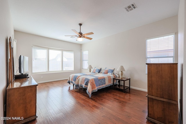 bedroom featuring ceiling fan, multiple windows, and dark hardwood / wood-style floors