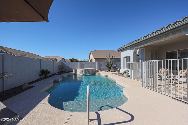 view of pool with a patio area, pool water feature, and a hot tub