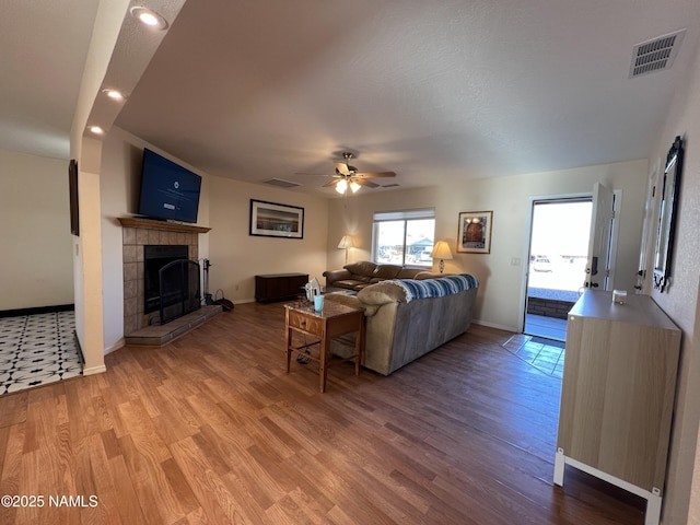 living room with a tiled fireplace, hardwood / wood-style floors, and ceiling fan