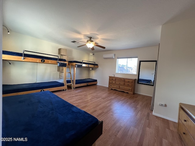 unfurnished bedroom featuring hardwood / wood-style flooring, ceiling fan, a wall mounted AC, and a textured ceiling