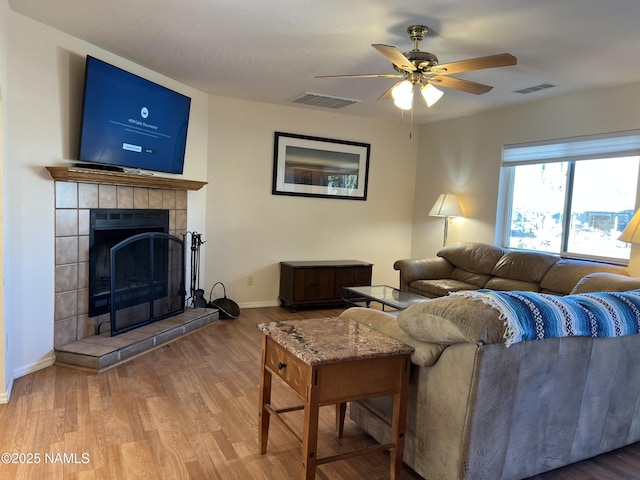 living room featuring wood-type flooring, ceiling fan, and a fireplace