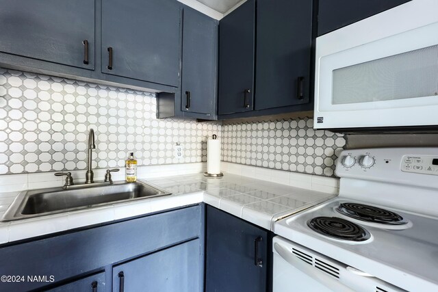 kitchen featuring sink, backsplash, white appliances, and blue cabinetry