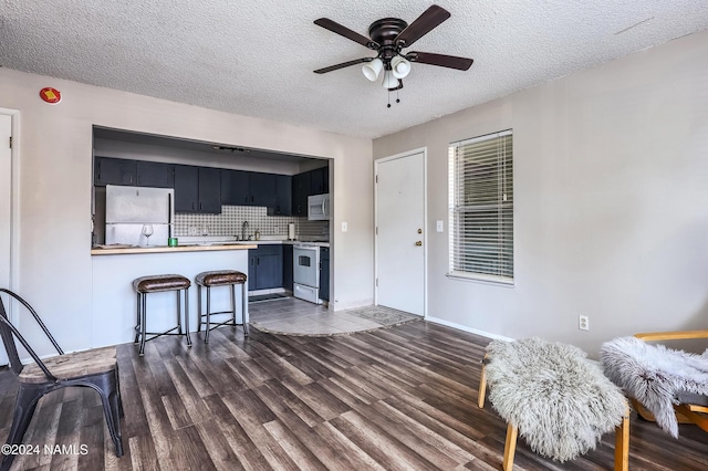 kitchen with fridge, a textured ceiling, sink, electric range, and kitchen peninsula