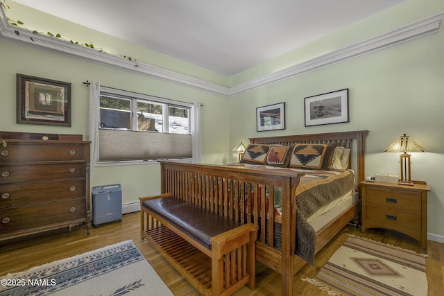 bedroom with a baseboard heating unit, baseboards, and wood finished floors