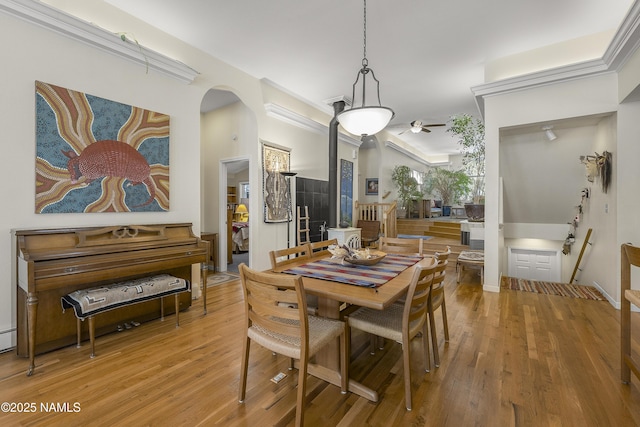 dining area featuring arched walkways and wood finished floors