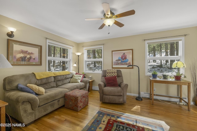 living room featuring ceiling fan, baseboards, baseboard heating, and wood finished floors